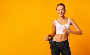 Girl In Oversize Jeans Gesturing Thumbs Up Smiling, Yellow Background